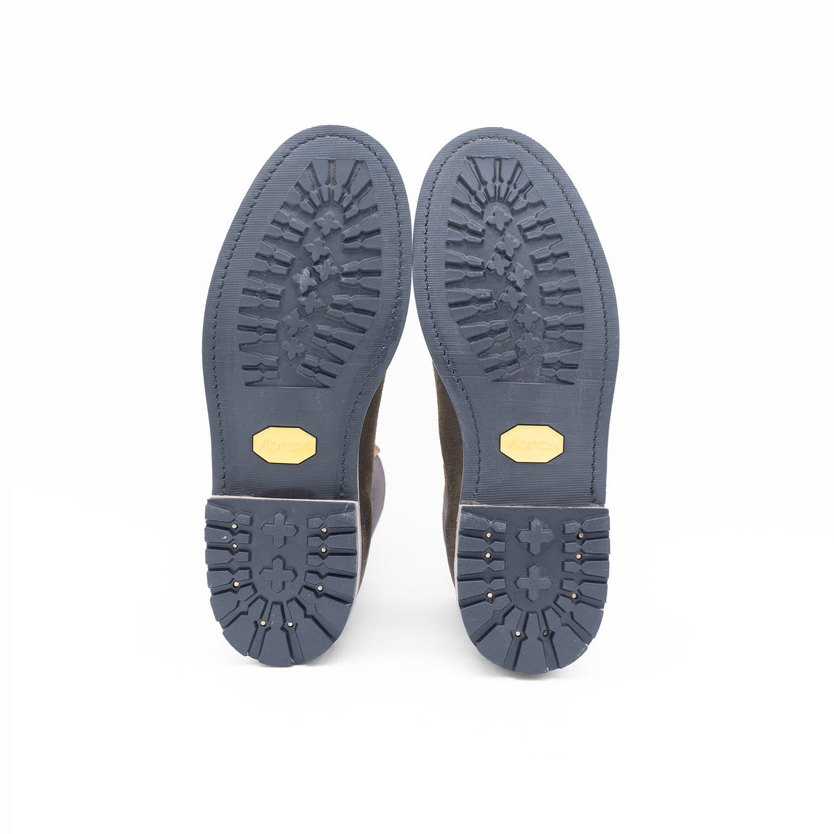 Close-up of the soles of a pair of shoes with visible brand logo on a white background